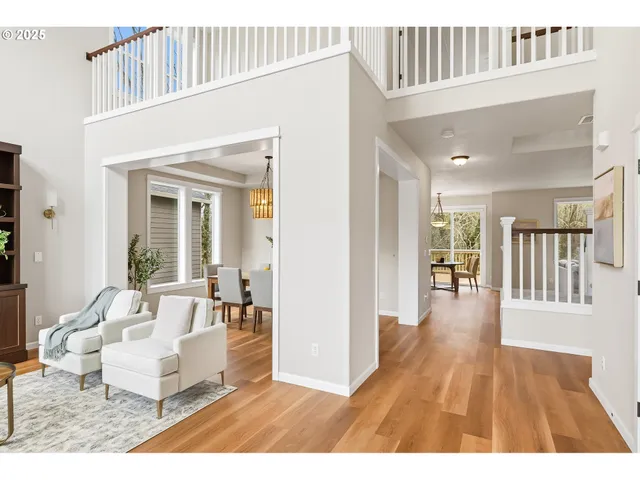 a living room with couches and a dining table with wooden floor
