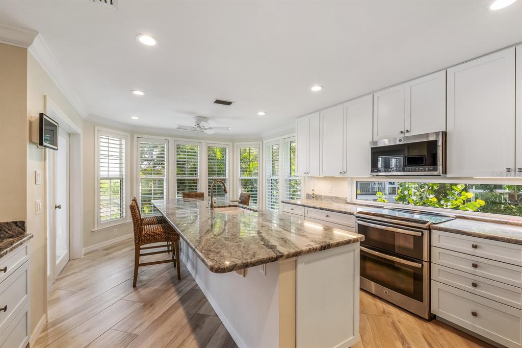 22 Seawatch Drive Boca Grande, FL 33921 - Photo 21 of 72 a kitchen with stainless steel appliances granite countertop a stove top oven a sink and dishwasher with wooden floor