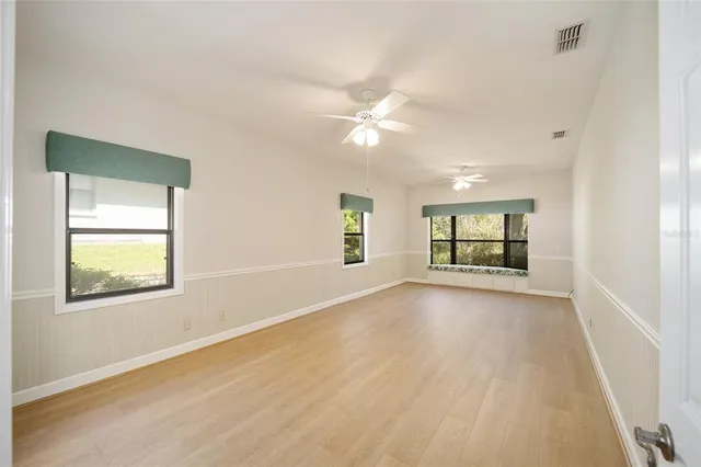 an empty room with windows and ceiling fan