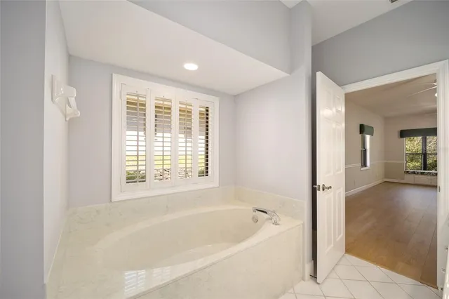 a white bath tub sitting in a en suite bathroom next to a window