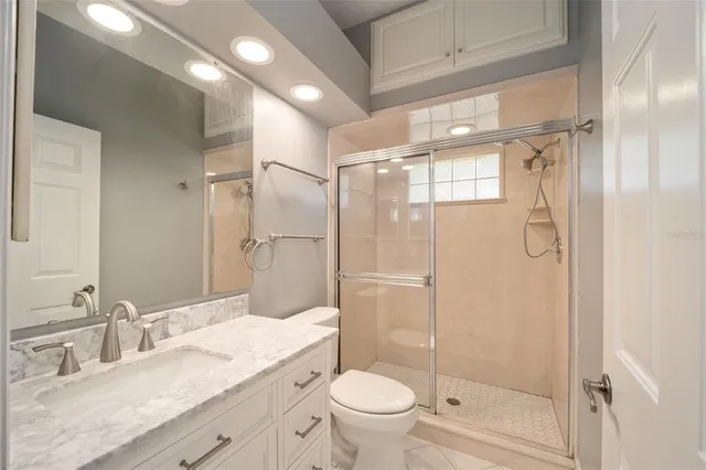 a bathroom with a granite countertop shower sink vanity mirror and toilet