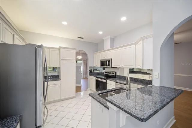 a kitchen with stainless steel appliances granite countertop a sink refrigerator and cabinets