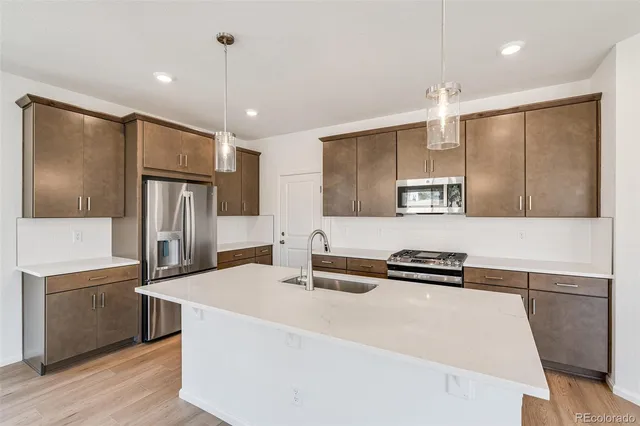 a kitchen with stainless steel appliances granite countertop a sink a stove and a refrigerator