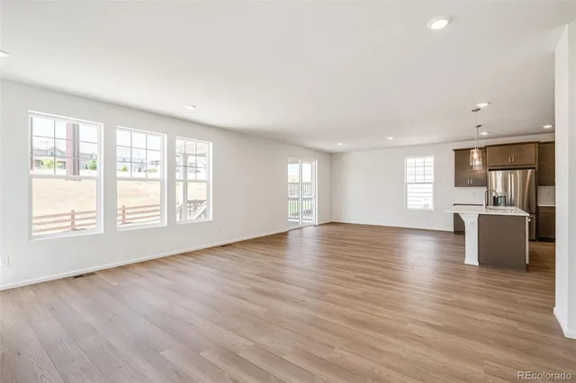 a view of an empty room with wooden floor fireplace and a window
