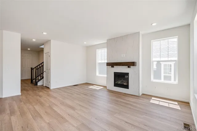 an empty room with wooden floor fireplace and windows