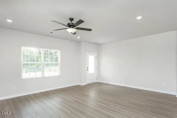 a view of an empty room with wooden floor and a window