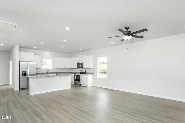 a open kitchen with kitchen island a sink appliances and cabinets