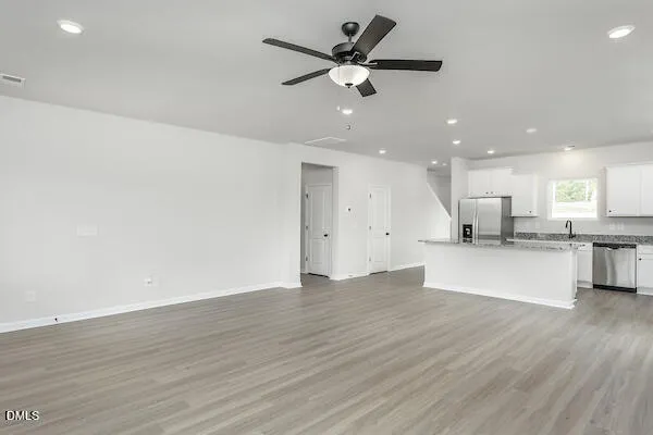 a view of an empty room with wooden floor and a ceiling fan
