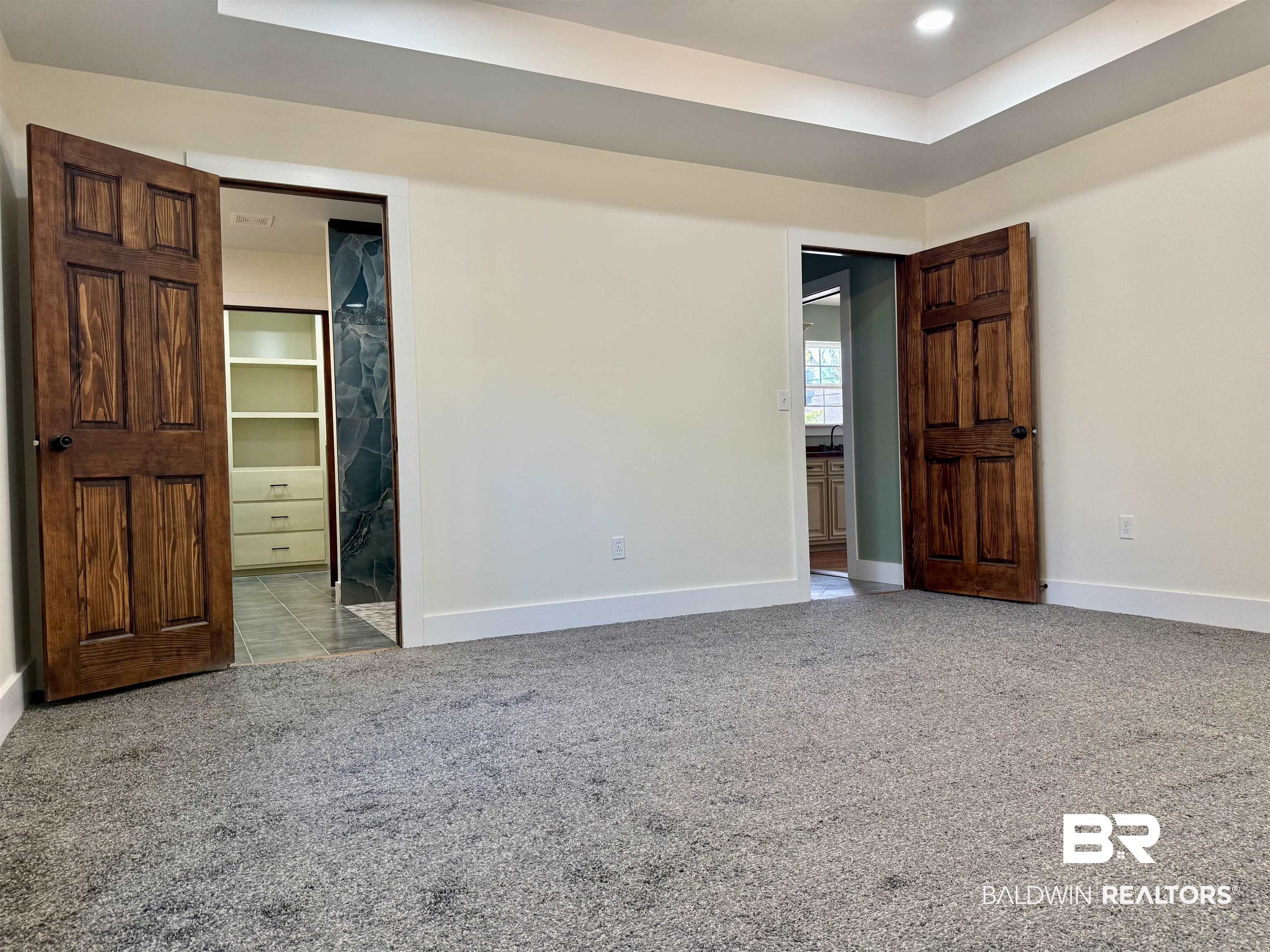 613 Forrest Avenue Brewton, AL 36426 - Photo 12 of 22 Unfurnished bedroom with ensuite bath, light colored carpet, a raised ceiling, and a spacious closet