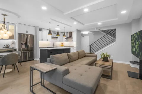 a living room with stainless steel appliances furniture a dining table and kitchen view