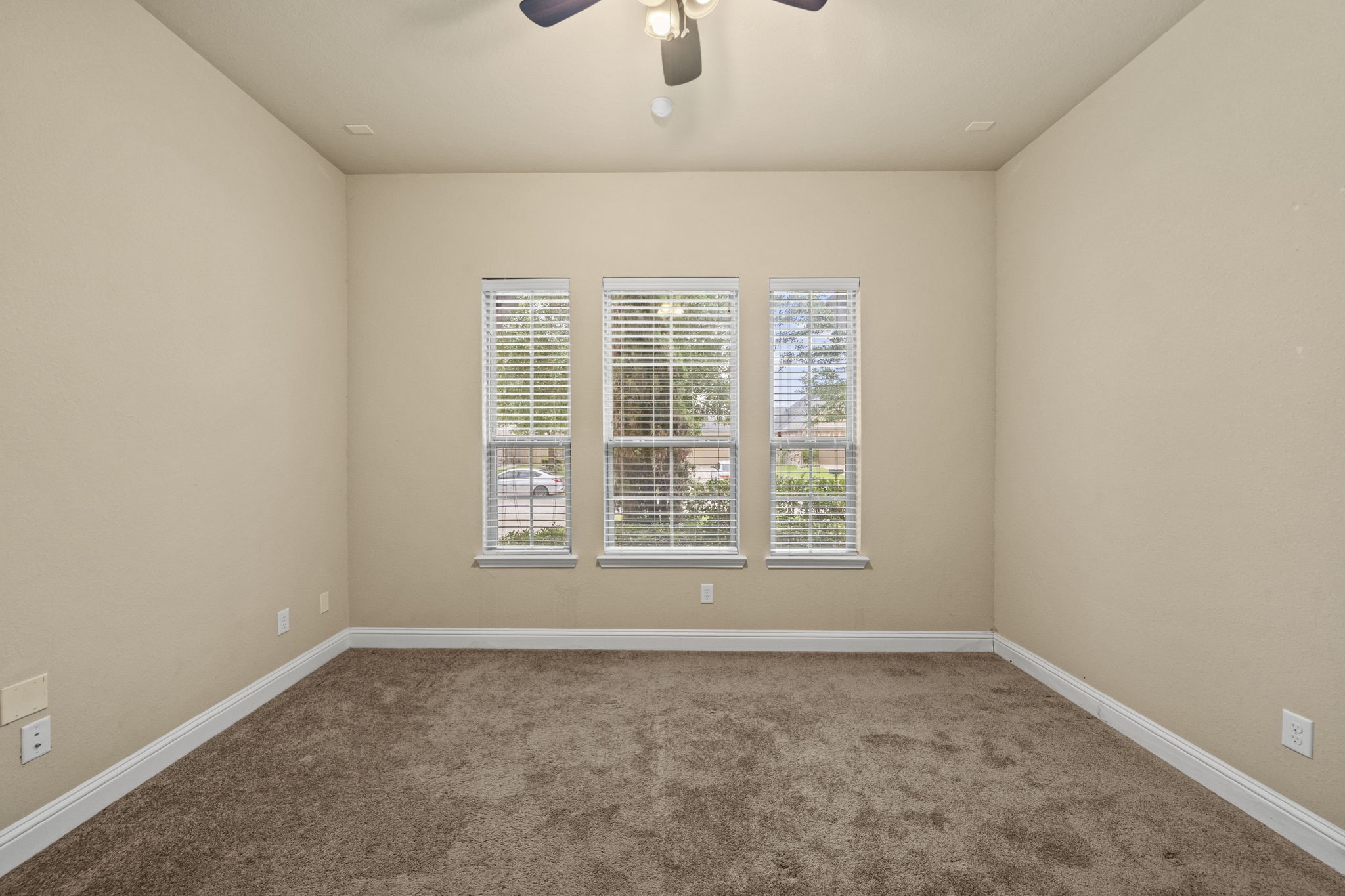 14215 Spindle Arbor Road Cypress, TX 77429 - Photo 37 of 47 This room features neutral walls, carpeted flooring, and three large windows with blinds, allowing natural light to fill the space. A ceiling fan provides comfort and circulation.