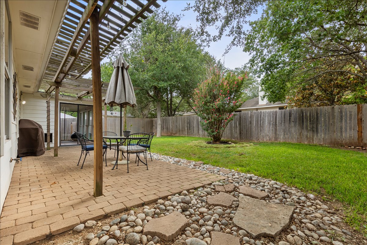 9012 Meacham Way Austin, TX 78749 - Photo 29 of 34 Expansive backyard featuring a paver patio with a wood pergola, manicured lawn, and a full privacy fence