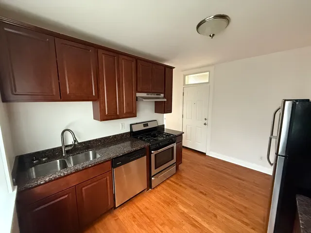 a kitchen with granite countertop wooden cabinets and a stove top oven