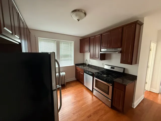 a kitchen with granite countertop wooden cabinets a refrigerator a sink and dishwasher