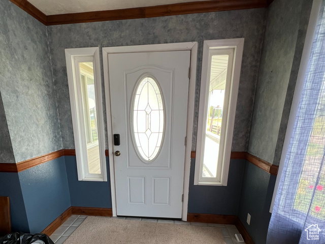 108 South Road Montpelier, ID 83254 - Photo 8 of 36 Entryway with a textured ceiling, light wood-style flooring, crown molding, wallpapered walls, and a wainscoted wall