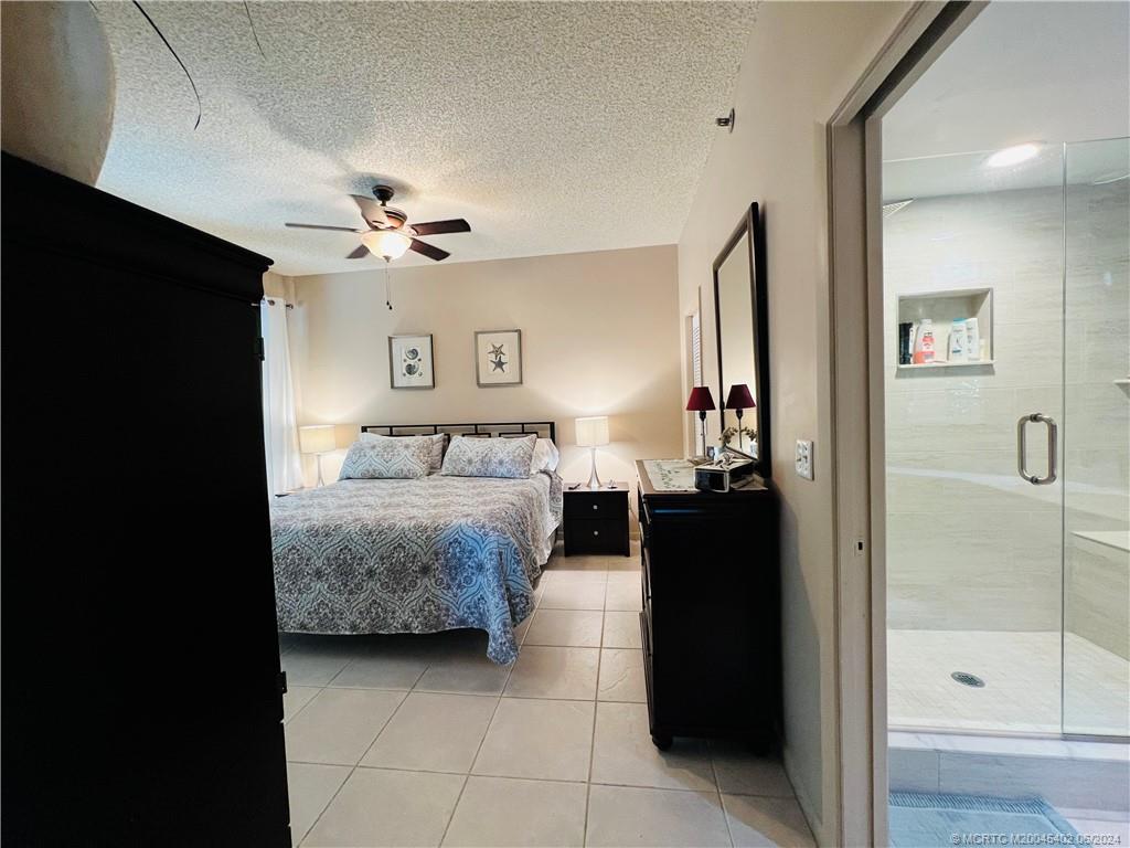221 Northeast Plantation Road, Unit 215 Stuart, FL 34996 - Photo 26 of 83 a bedroom with a bed and a chandelier