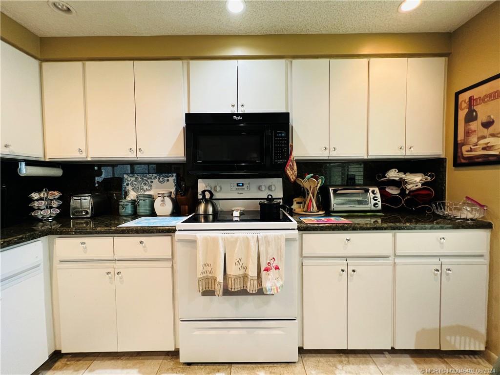 221 Northeast Plantation Road, Unit 215 Stuart, FL 34996 - Photo 44 of 83 a kitchen with stainless steel appliances granite countertop a stove a sink and white cabinets