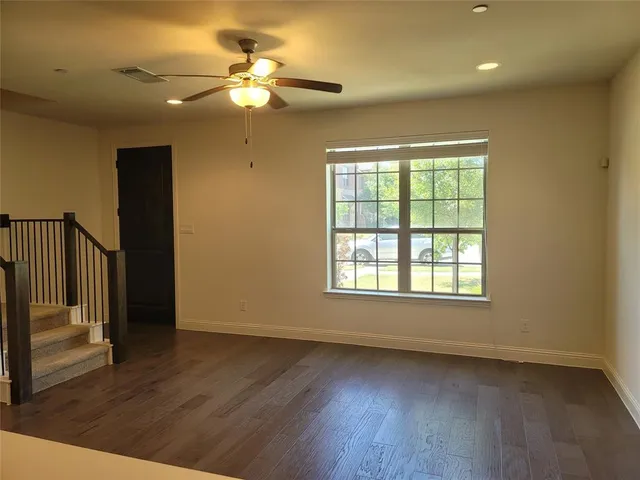 an empty room with wooden floor fan and windows