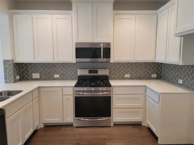a kitchen with white cabinets and a stove