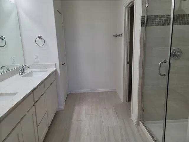 a spacious bathroom with a granite countertop sink a mirror and shower