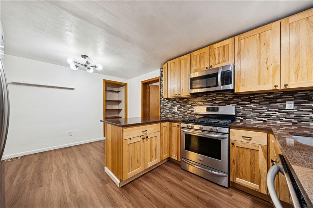 910 Colonial Manor Road Irwin, PA 15642 - Photo 11 of 40 a kitchen with granite countertop wooden floors and stainless steel appliances