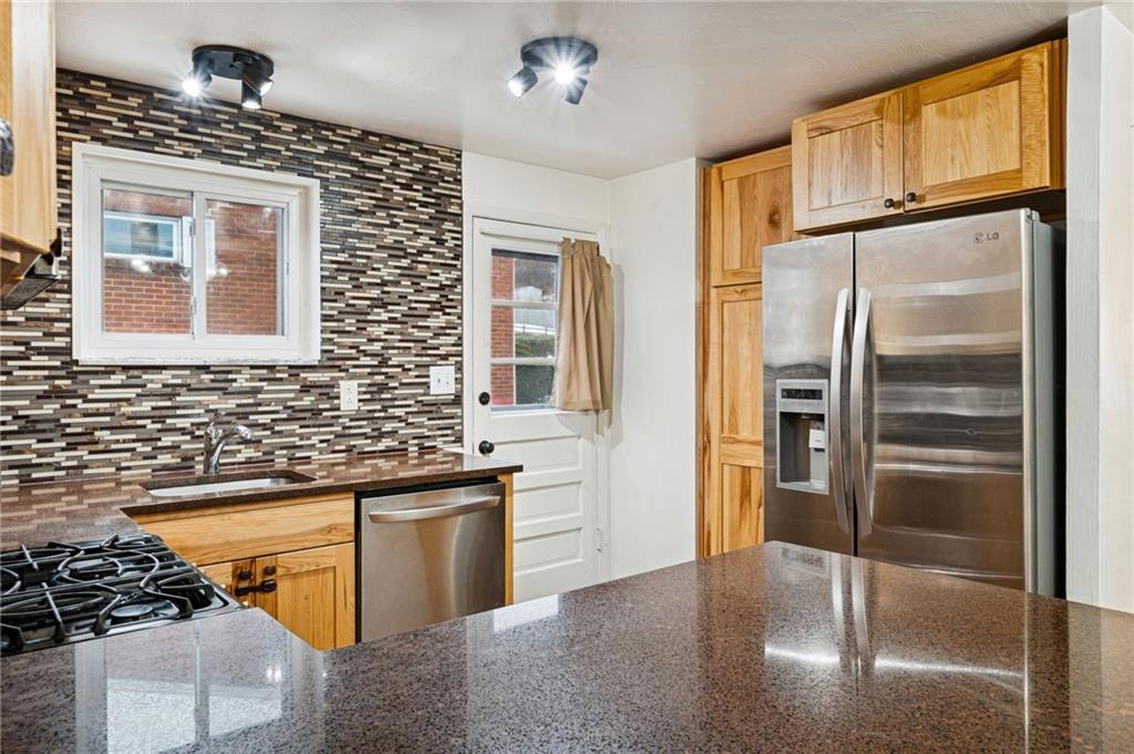 910 Colonial Manor Road Irwin, PA 15642 - Photo 14 of 40 a kitchen with stainless steel appliances granite countertop a refrigerator a oven and white cabinets with wooden floors