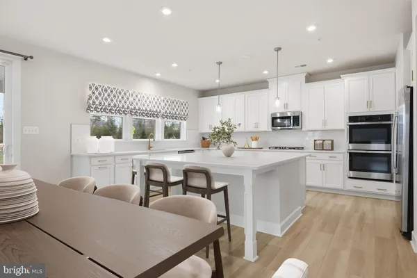 a kitchen with kitchen island white cabinets and stainless steel appliances