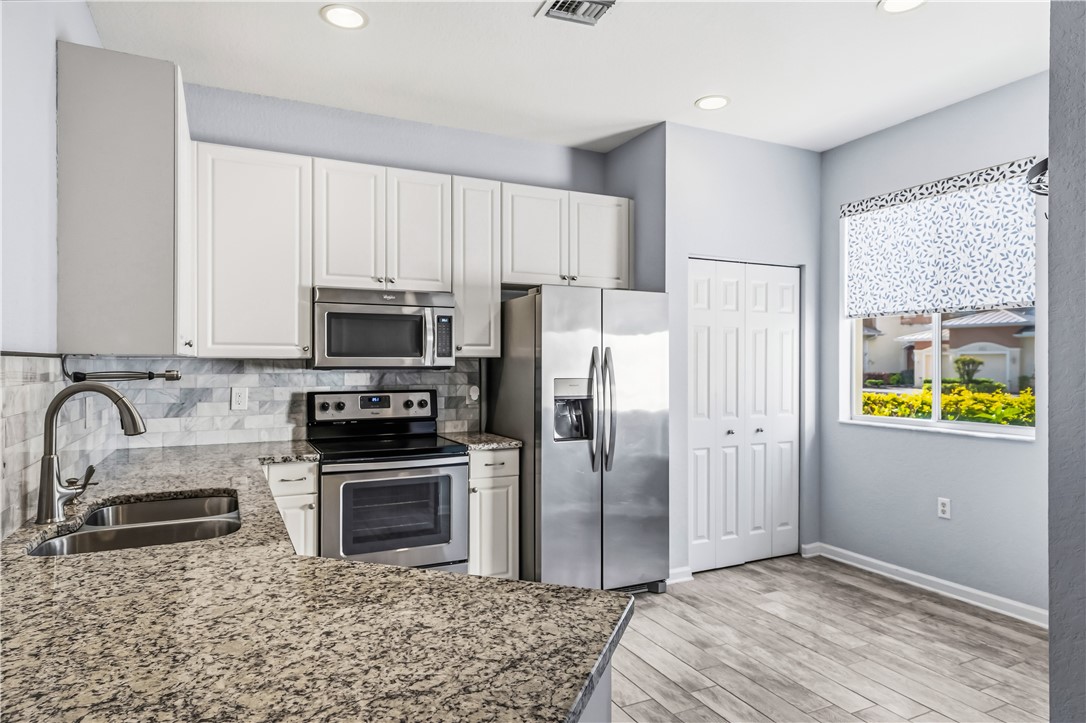 2522 Stockbridge Square Southwest Vero Beach, FL 32962 - Photo 13 of 34 a kitchen with stainless steel appliances a stove a refrigerator a sink a counter space and cabinets