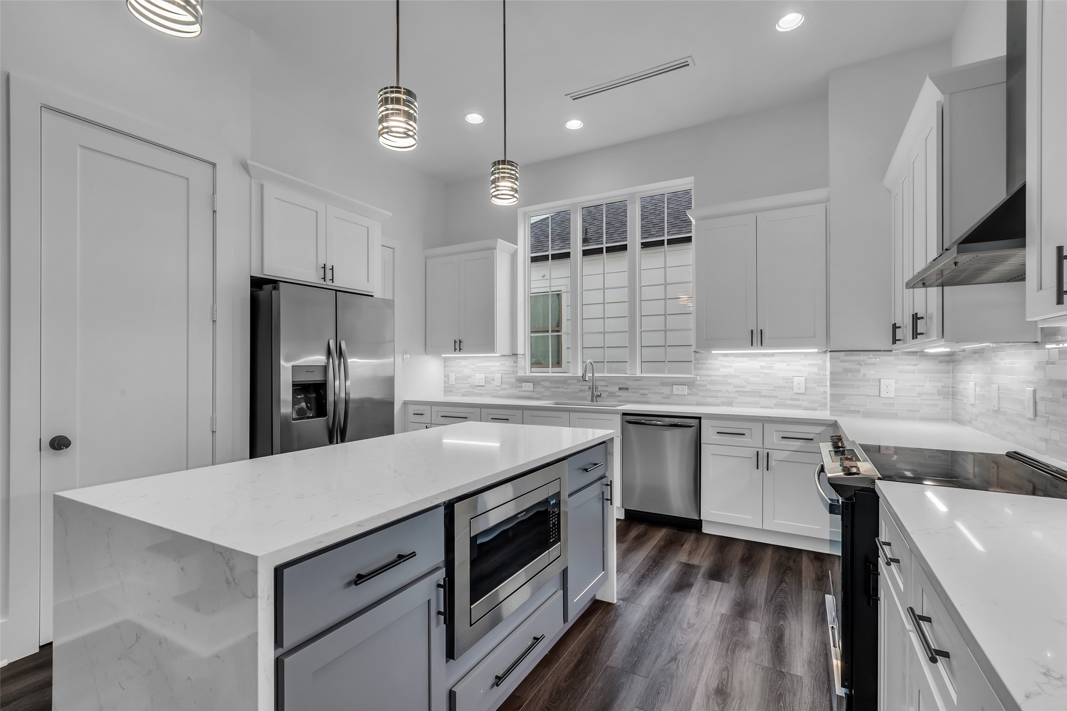 2716 Baldwin Street Houston, TX 77006 - Photo 4 of 26 Located on the second floor, this modern kitchen features white quartz countertops and a sleek white-gray tile backsplash, combining style with everyday functionality.