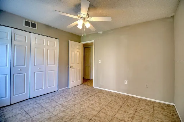 an empty room with a chandelier fan and closet