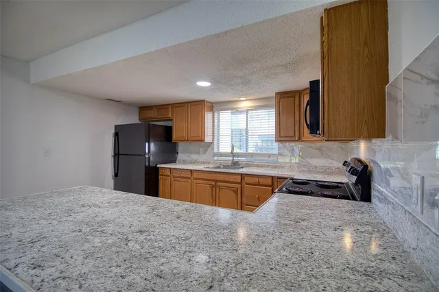 a kitchen with granite countertop a refrigerator and a sink