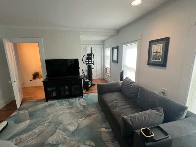 a bedroom with a bed couch and a large window with wooden floor