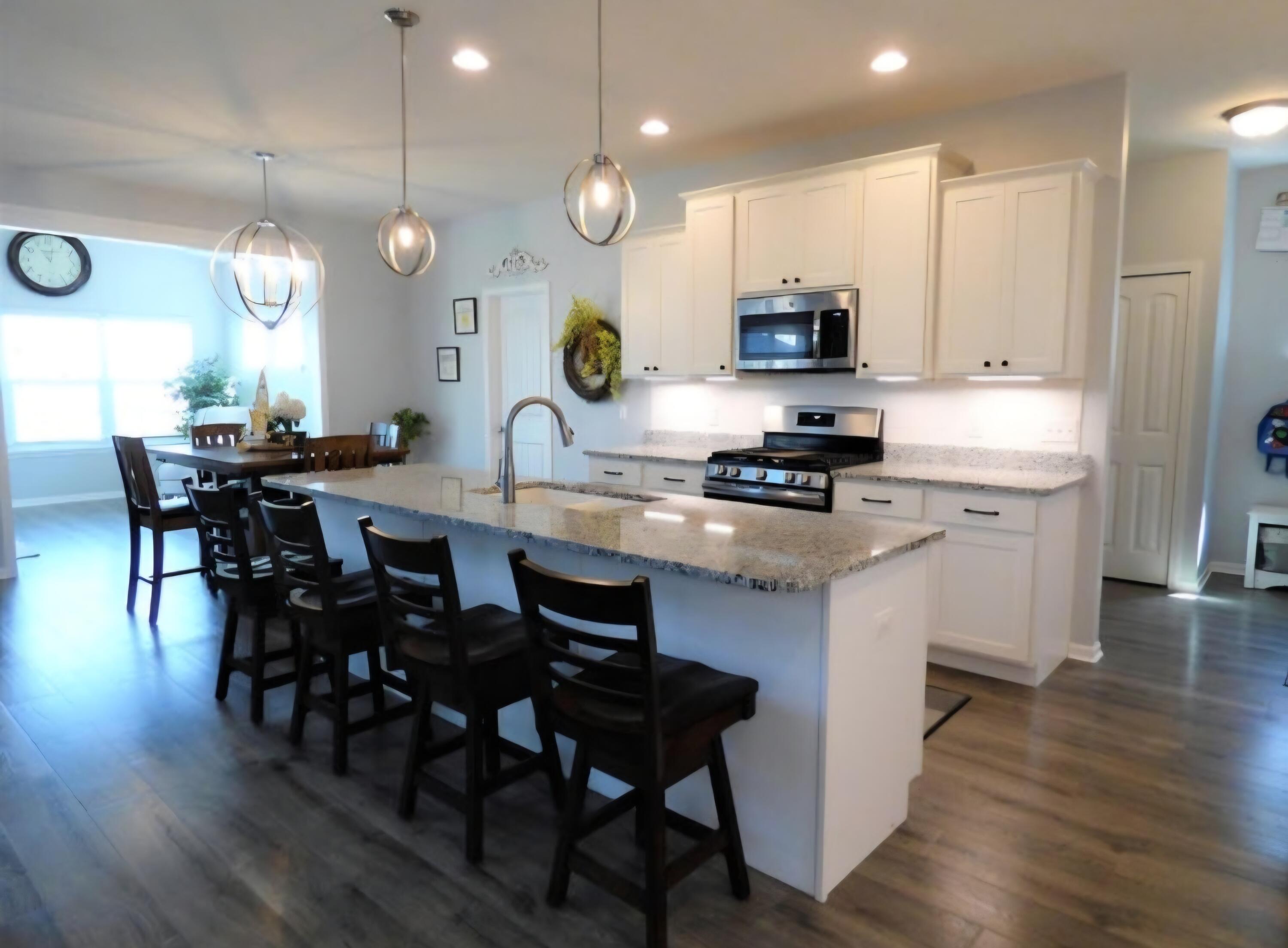 636 East 119th Place Crown Point, IN 46307 - Photo 4 of 35 a kitchen with stainless steel appliances granite countertop a stove a sink dishwasher a microwave oven with a dining table and chairs with wooden floor