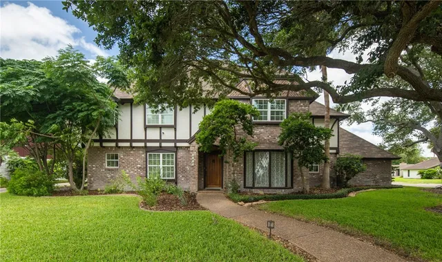 front view of a house with a yard and an trees