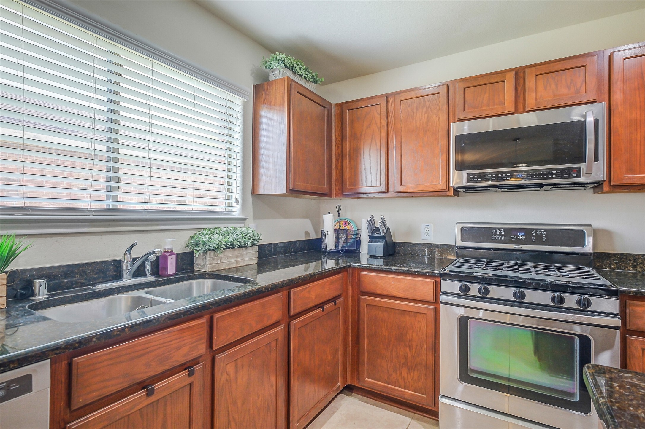 1015 Honeysuckle Vine Drive Rosenberg, TX 77469 - Photo 11 of 29 a kitchen with granite countertop a sink a stove a microwave cabinets and a window