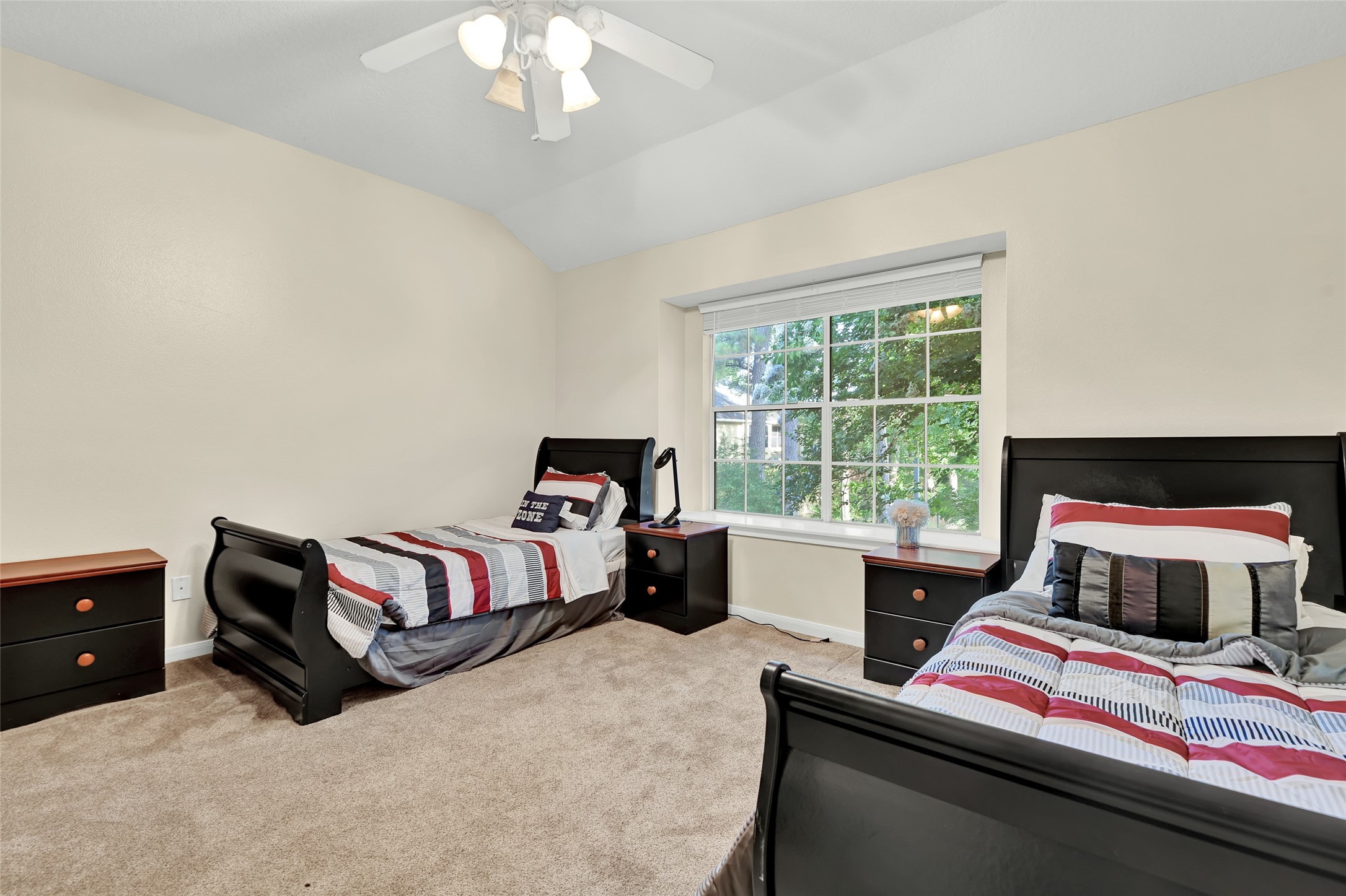 14420 Walters Road, Unit 16 Houston, TX 77014 - Photo 22 of 27 This bedroom features two twin beds with matching dark wood furniture, including nightstands. A large window allows natural light to fill the space, and the neutral walls provide a warm, inviting atmosphere. The room also includes a ceiling fan and carpeted flooring for comfort.