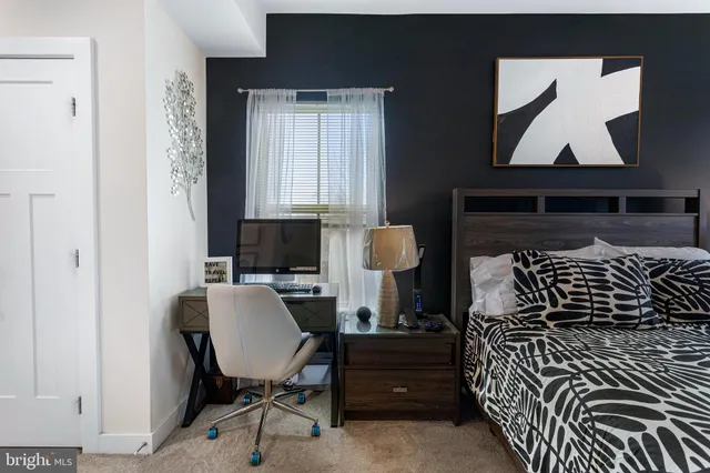 a bedroom with a bed a rug and a potted plant