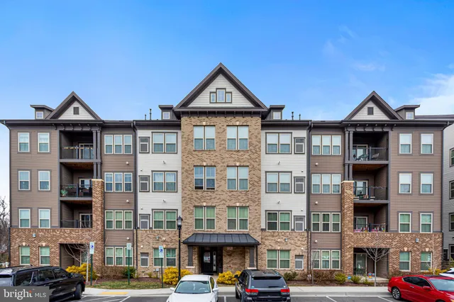 a front view of a building with lot of cars and trees