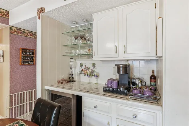 a kitchen with stainless steel appliances a refrigerator a sink dishwasher a dining table and chairs with wooden floor