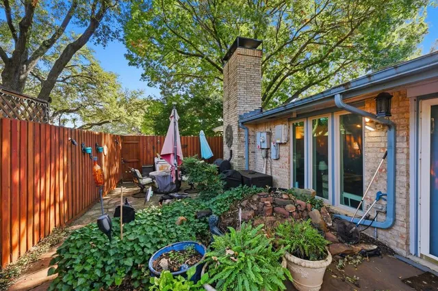 a view of a backyard with potted plants and large trees
