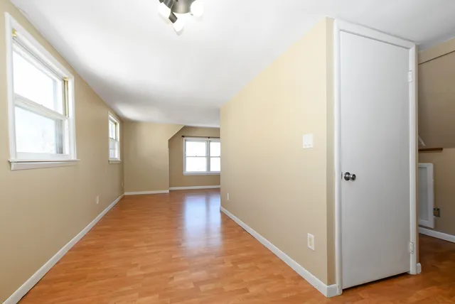 a view of an empty room with window and wooden floor