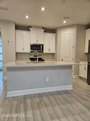 a large kitchen with stainless steel appliances a large counter top and kitchen floors