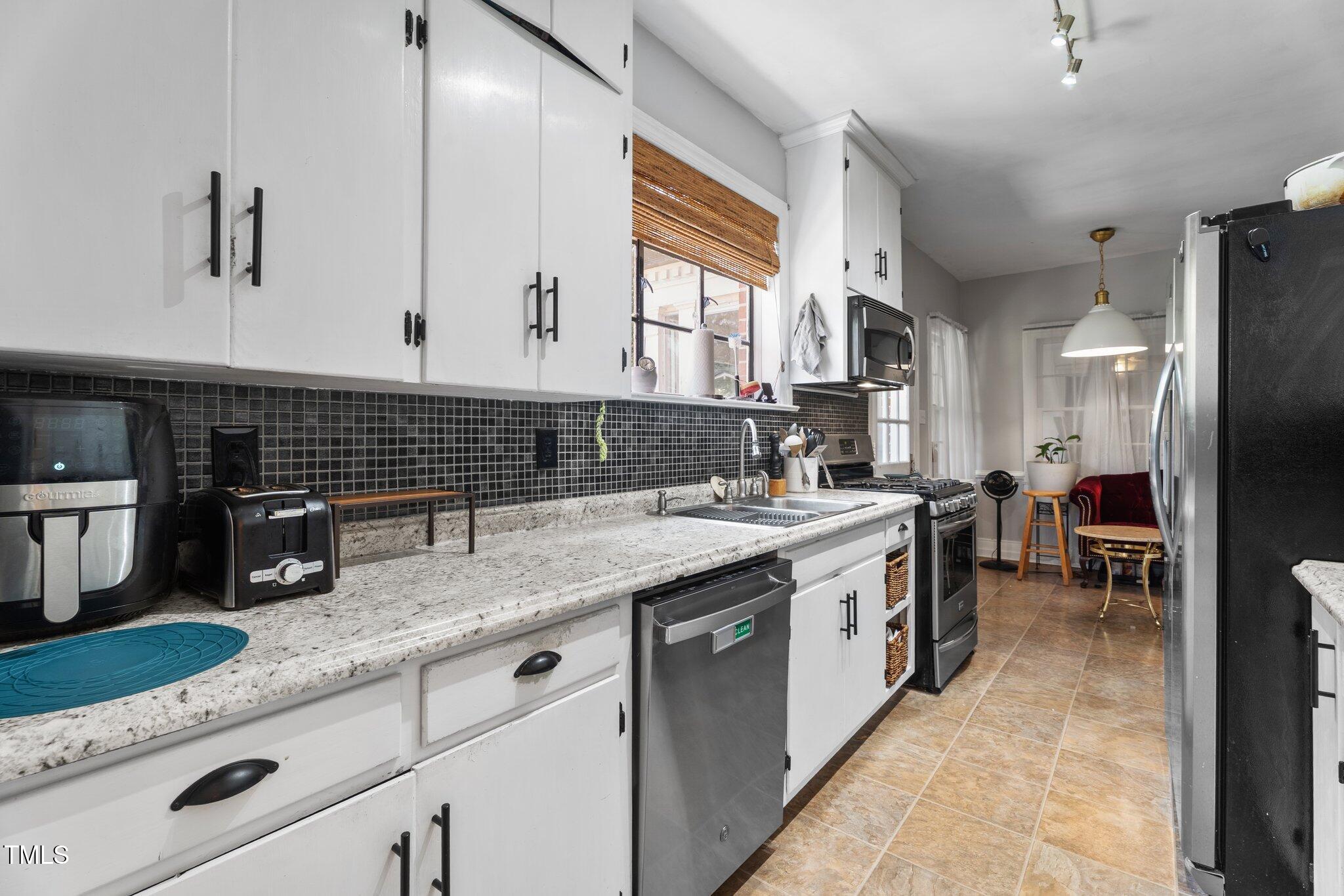 925 South Chestnut Street Henderson, NC 27536 - Photo 7 of 28 a kitchen with granite countertop stainless steel appliances a sink window and cabinets
