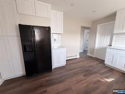 a view of a kitchen with refrigerator and wooden floor
