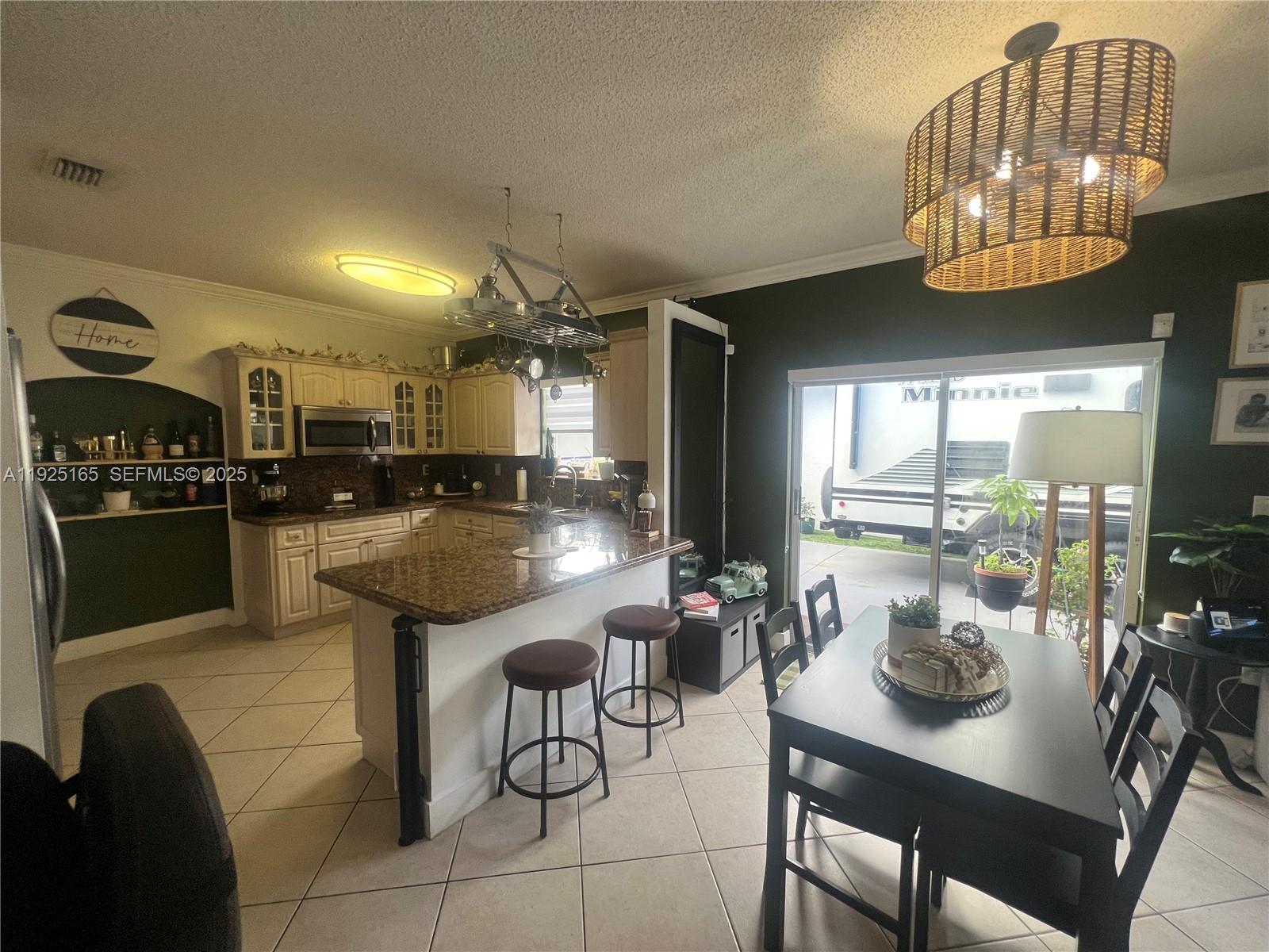 12446 Southwest 198th Street Miami, FL 33177 - Photo 17 of 56 a kitchen with stainless steel appliances kitchen island granite countertop a table and chairs in it