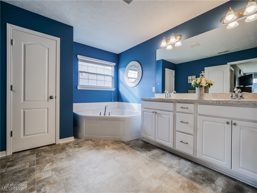 37571 Amber Way North Ridgeville, OH 44039 - Photo 19 of 35 Bathroom featuring a tub, a textured ceiling, tile floors, double sink vanity, and a chandelier