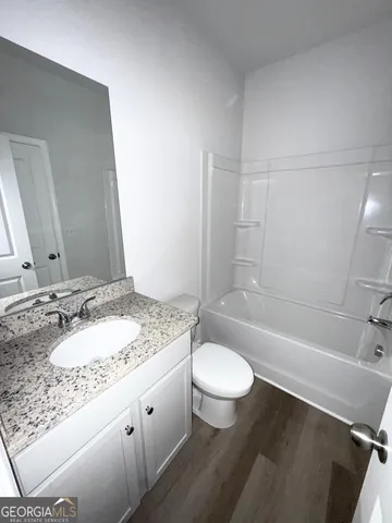 a bathroom with a granite countertop sink toilet a mirror and bathtub