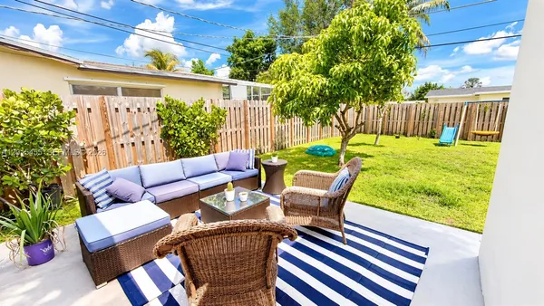 a view of a patio with couches chairs potted plants and wooden fence