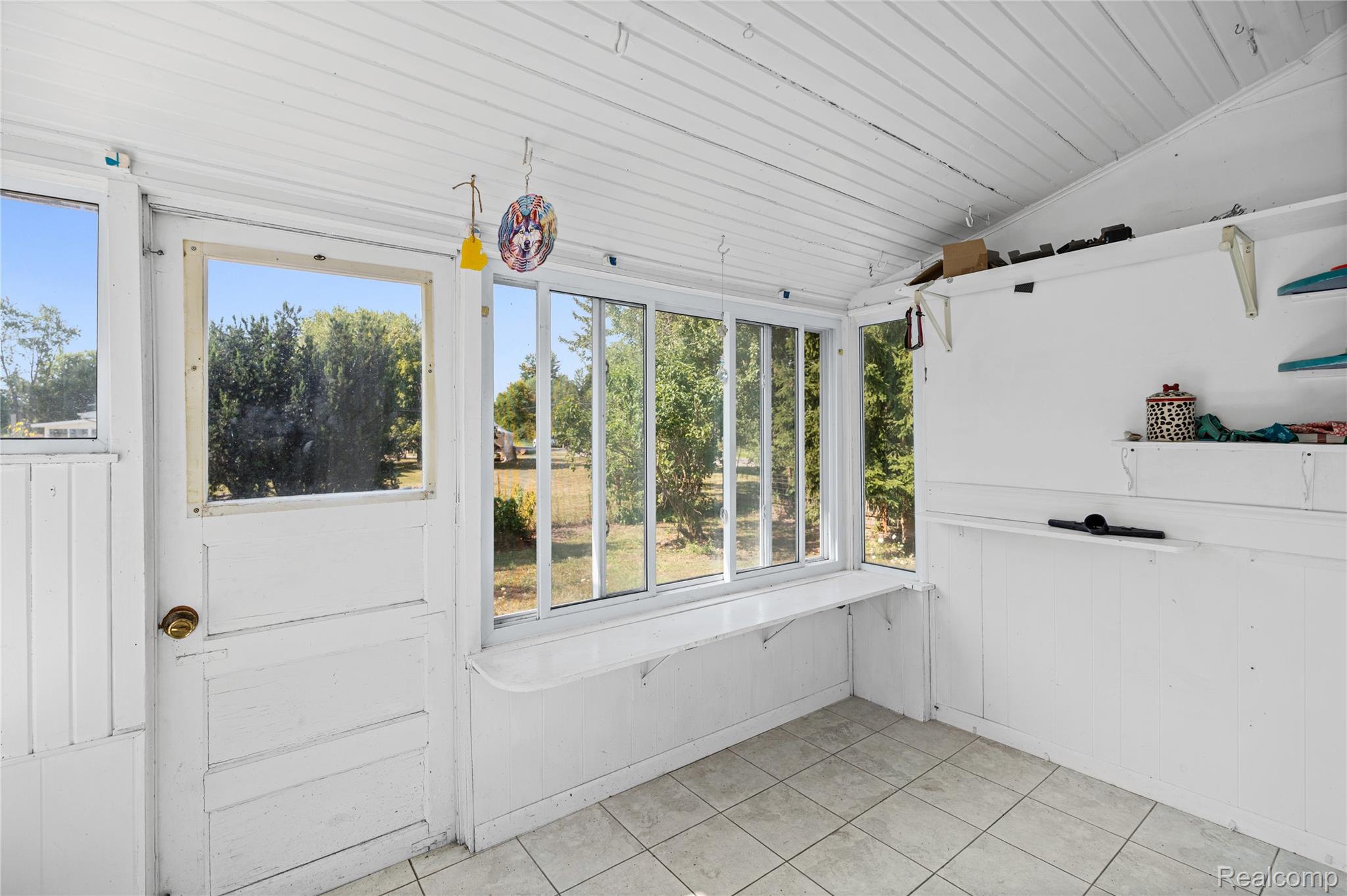 1175 South Morrish Road Flint, MI 48532 - Photo 36 of 72 Sunroom featuring tile flooring, white planked walls, built-in shelving, and multiple windows