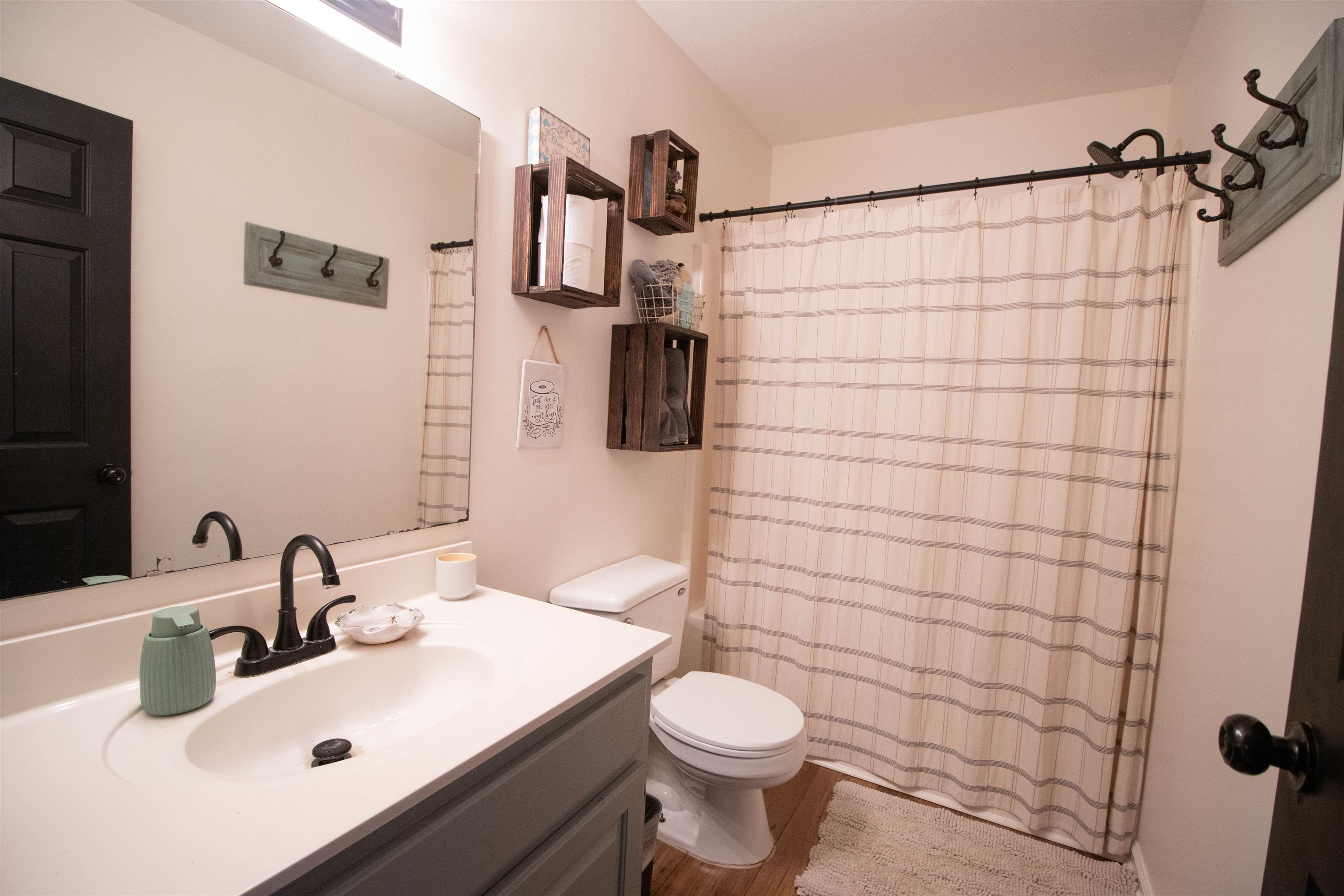 120 Craig Road Ripley, TN 38063 - Photo 22 of 38 Bathroom featuring a single vanity with an integrated sink, dark bronze hardware, a full-width mirror, and wood-finish flooring